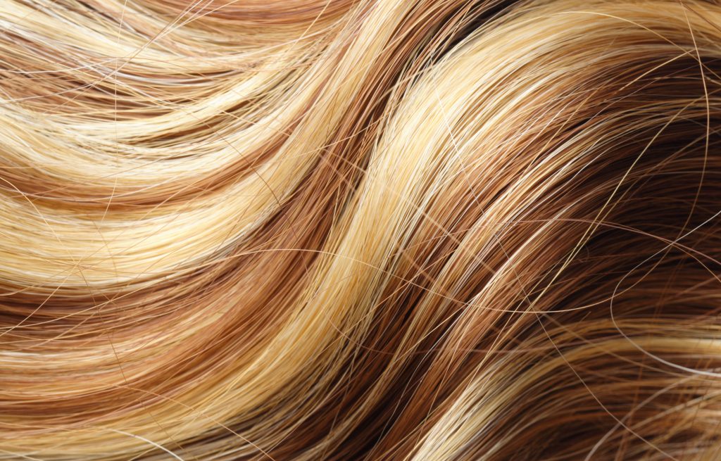 : Close-up of golden blonde hair with lighter blonde highlights adding brightness and dimension for a spring hair color look.