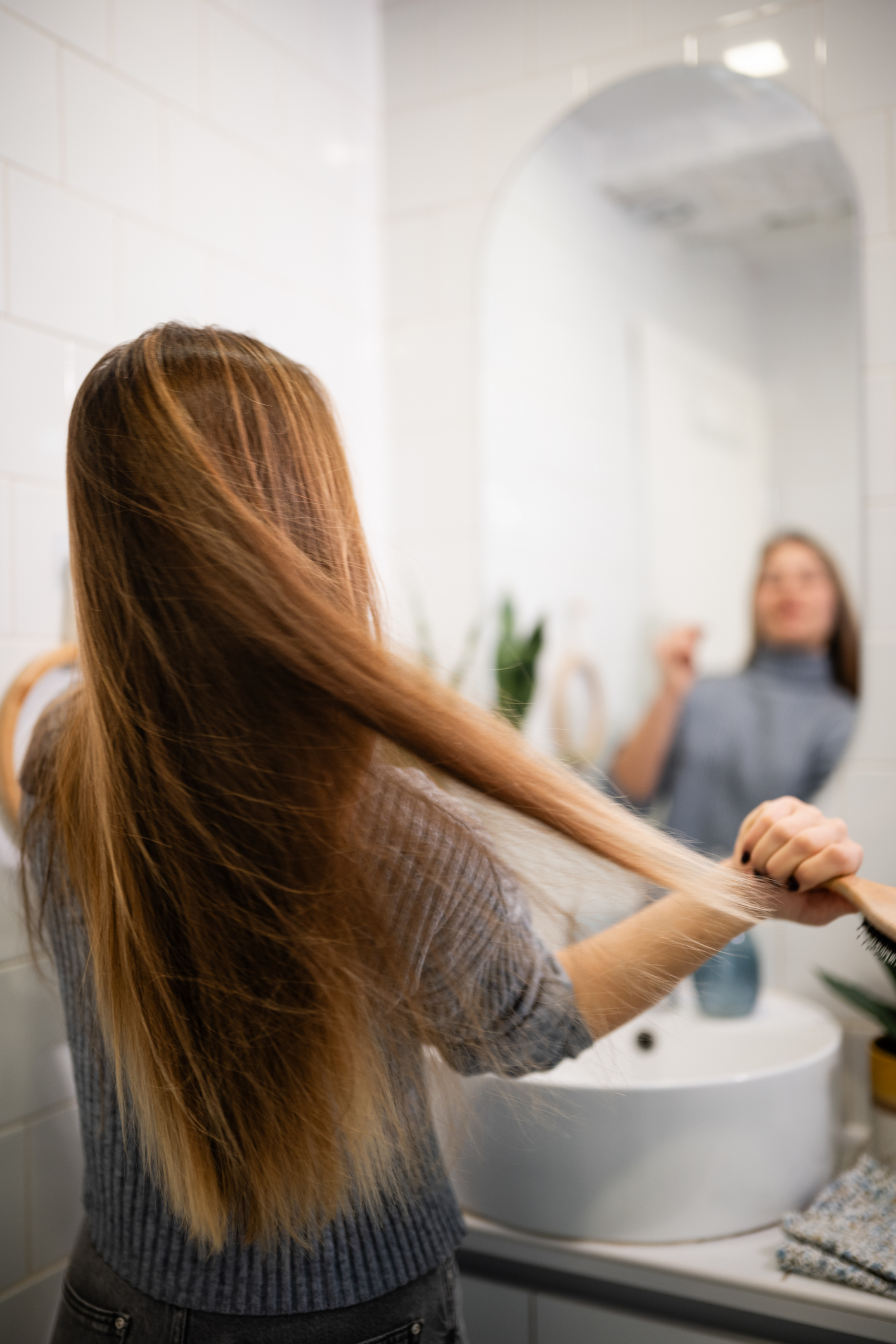 Woman brushing hair before shampooing — healthy hair tip from Salon International in Mount Pleasant, SC.